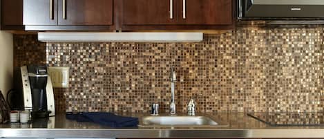 A kitchen with dark wooden cabinets, a stainless steel sink, a coffee maker, and a dishwasher.