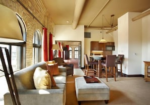 A spacious living area with a sofa, ottoman, and dining table with chairs. - The Brewhouse Inn & Suites (Milwaukee)