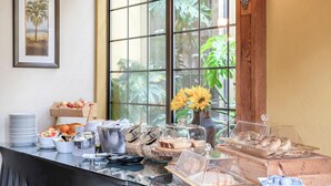 A breakfast buffet with various food items and a vase of yellow flowers.