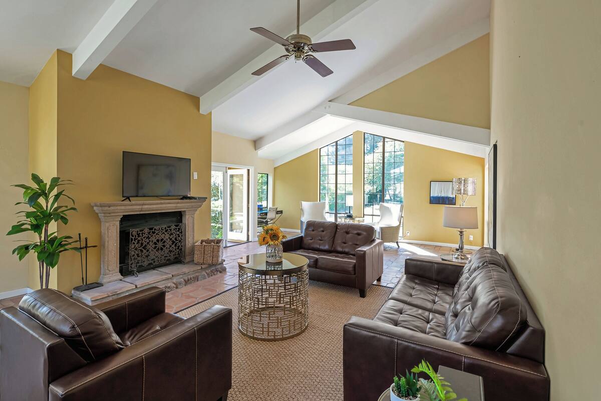 A spacious living room with a fireplace, leather sofas, a coffee table, and a television.