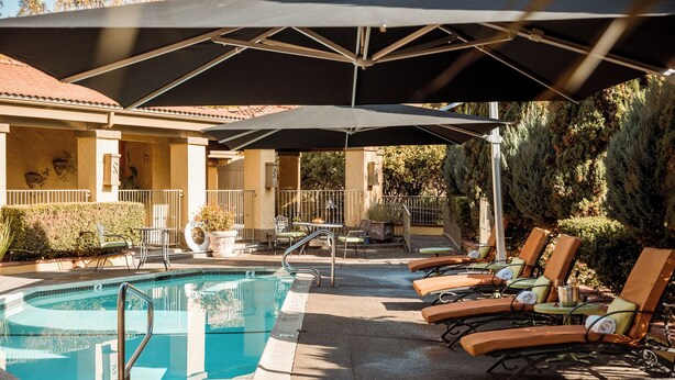 A poolside area with lounge chairs, umbrellas, and a pool.