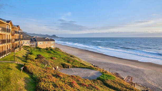 A coastal hotel with a beach view, a paved walkway, and a small circular area. - Cavalier Beachfront Condominiums (Lincoln City)