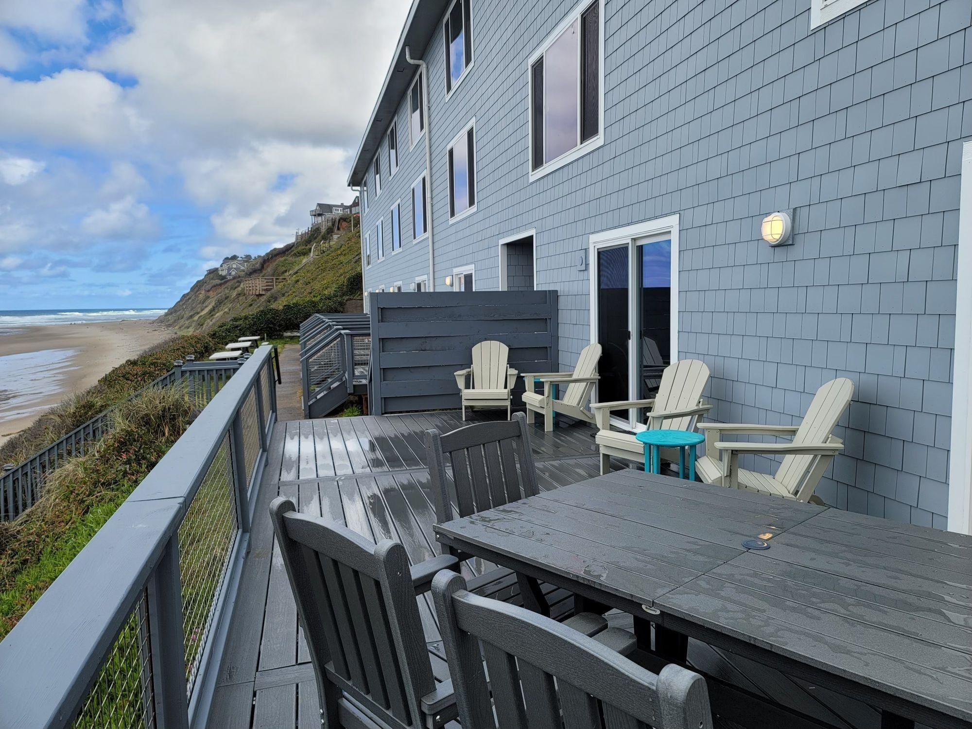 A deck with a table and chairs overlooking a beach.