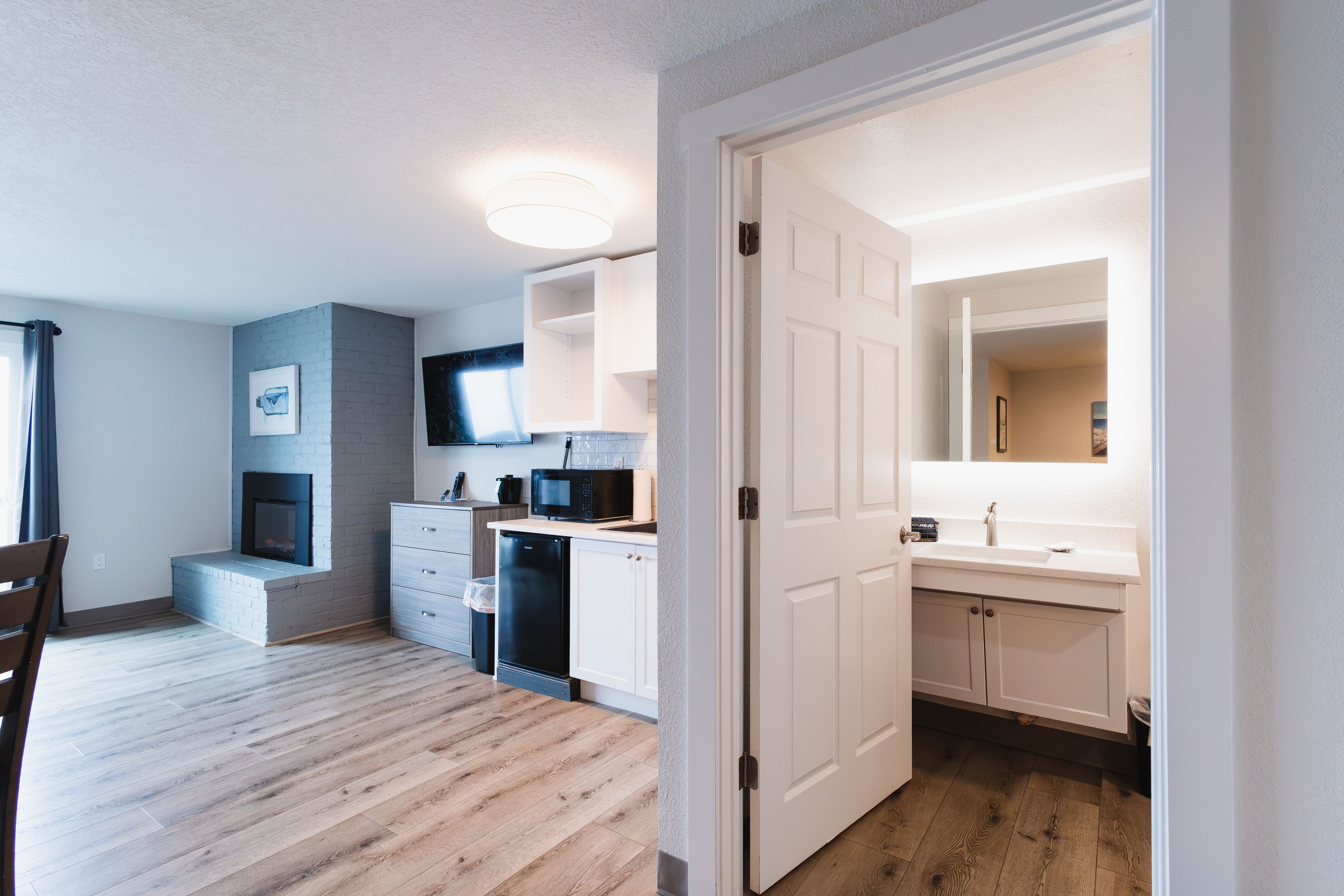 A modern kitchen with white cabinetry, a built-in microwave, and a flat-screen TV mounted above the counter.