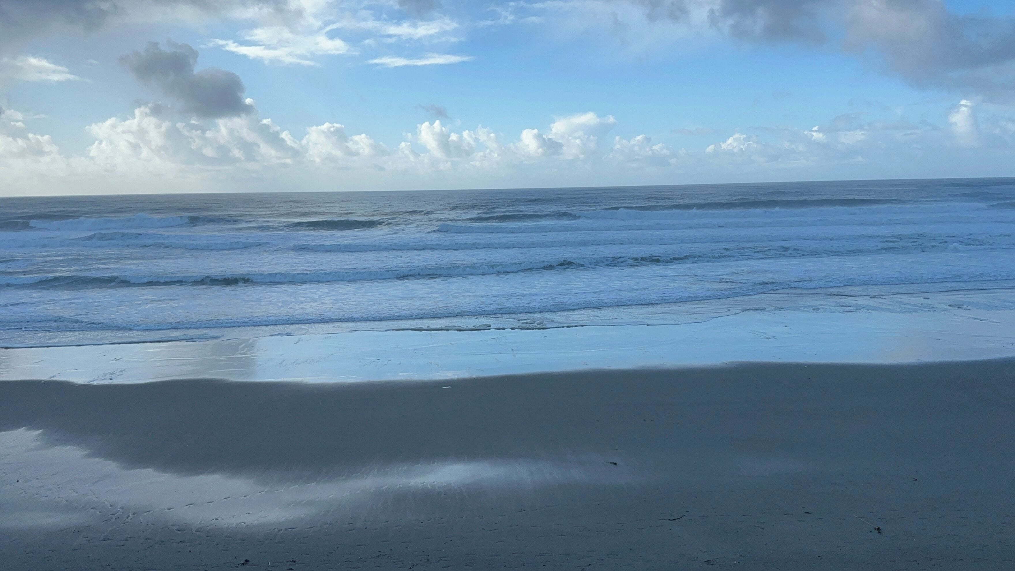 A beach with waves and a clear sky.