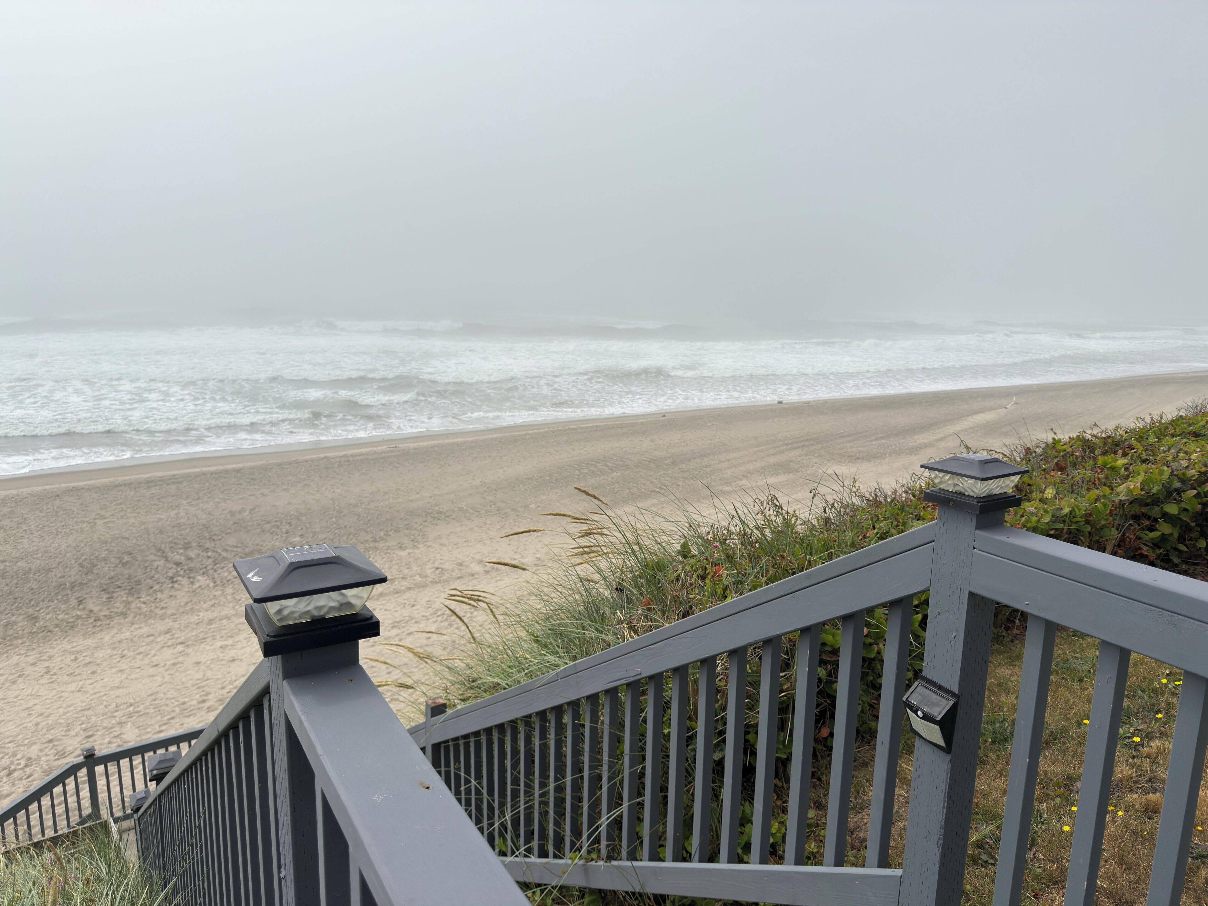 A wooden staircase leading to a beach with a view of the ocean.