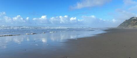 A wide sandy beach with gentle waves and a clear sky.