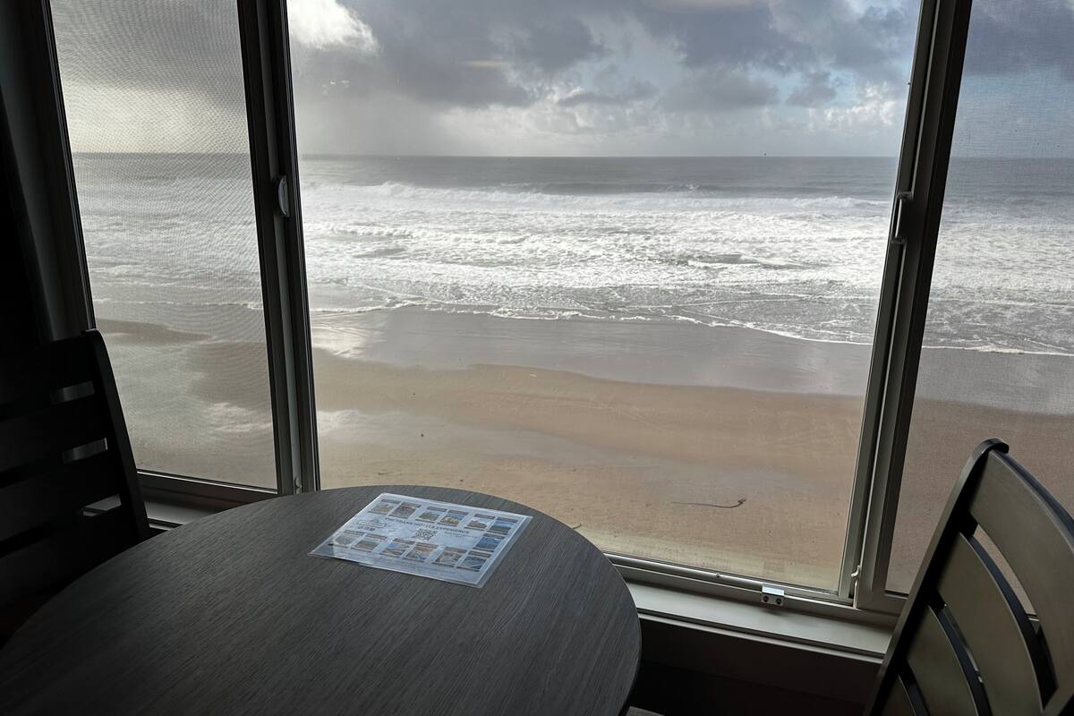A room with a large window overlooking a beach.