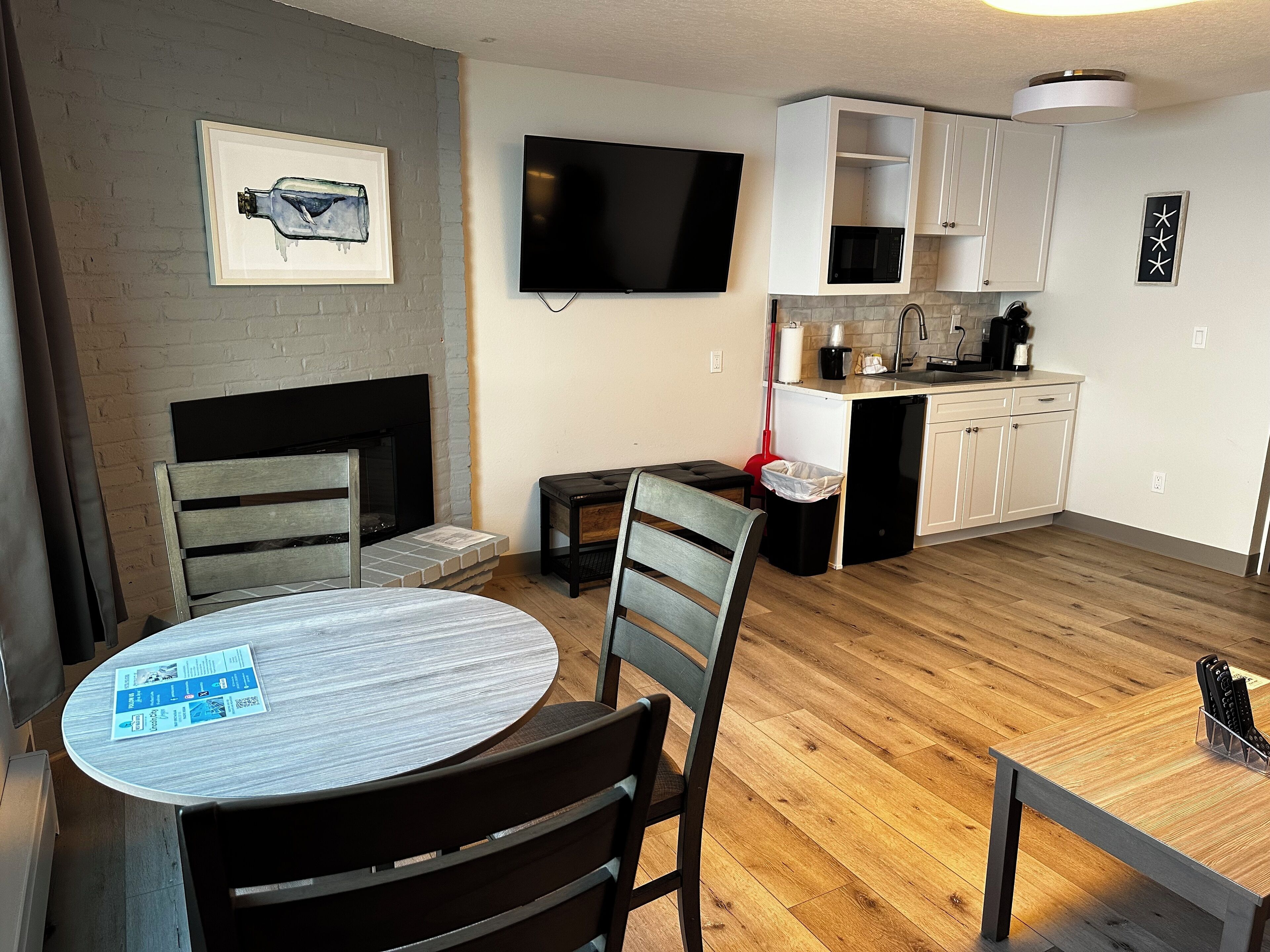 A modern kitchen with white cabinets, a flat-screen TV, a microwave, and a coffee maker.