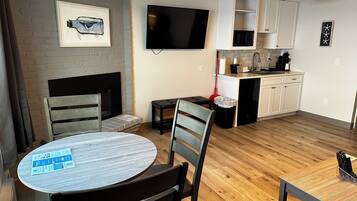 A modern kitchen with white cabinets, a flat-screen TV, a microwave, and a coffee maker.