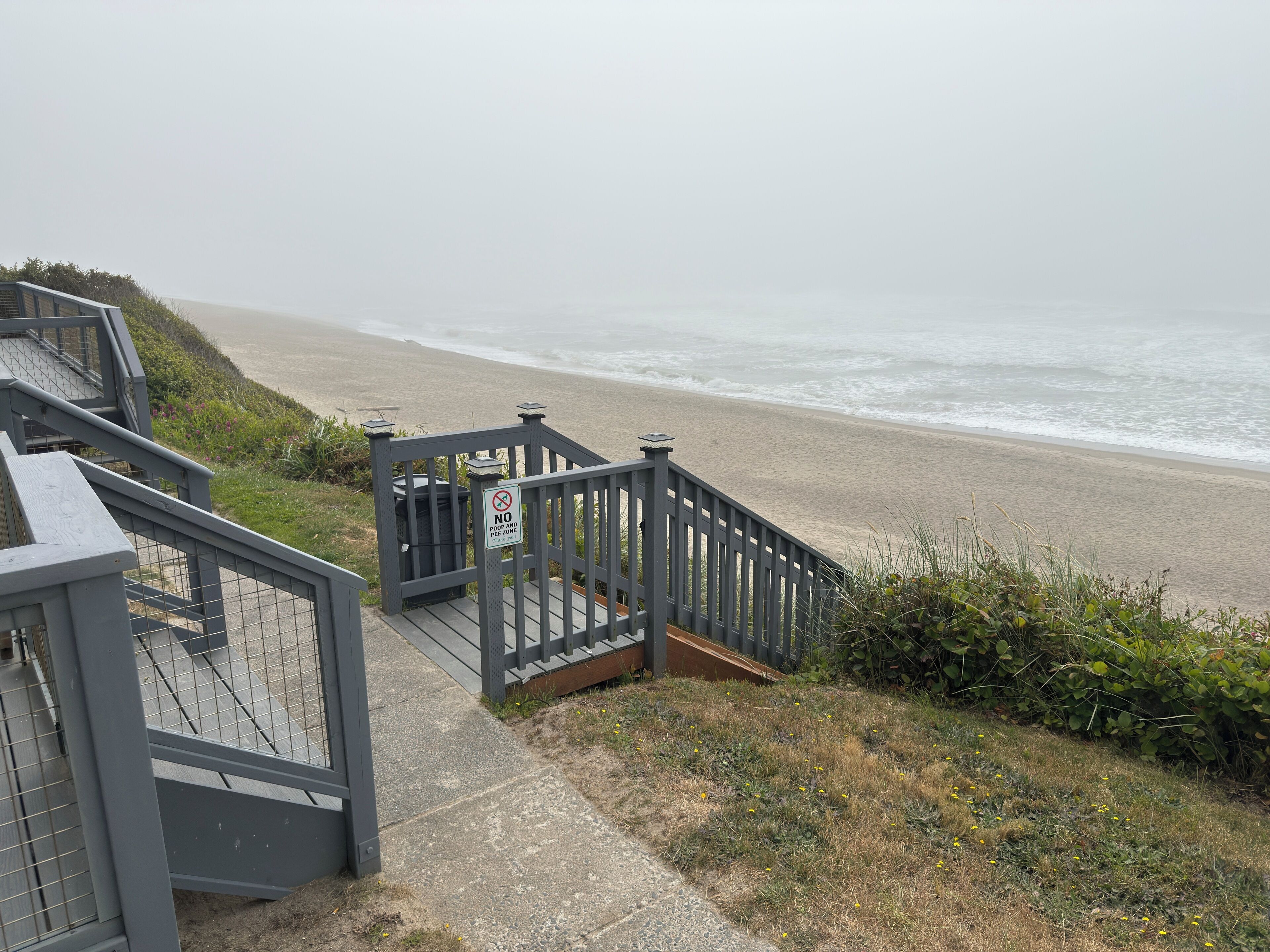 A wooden staircase leading to a beach with a 'No Parking' sign.