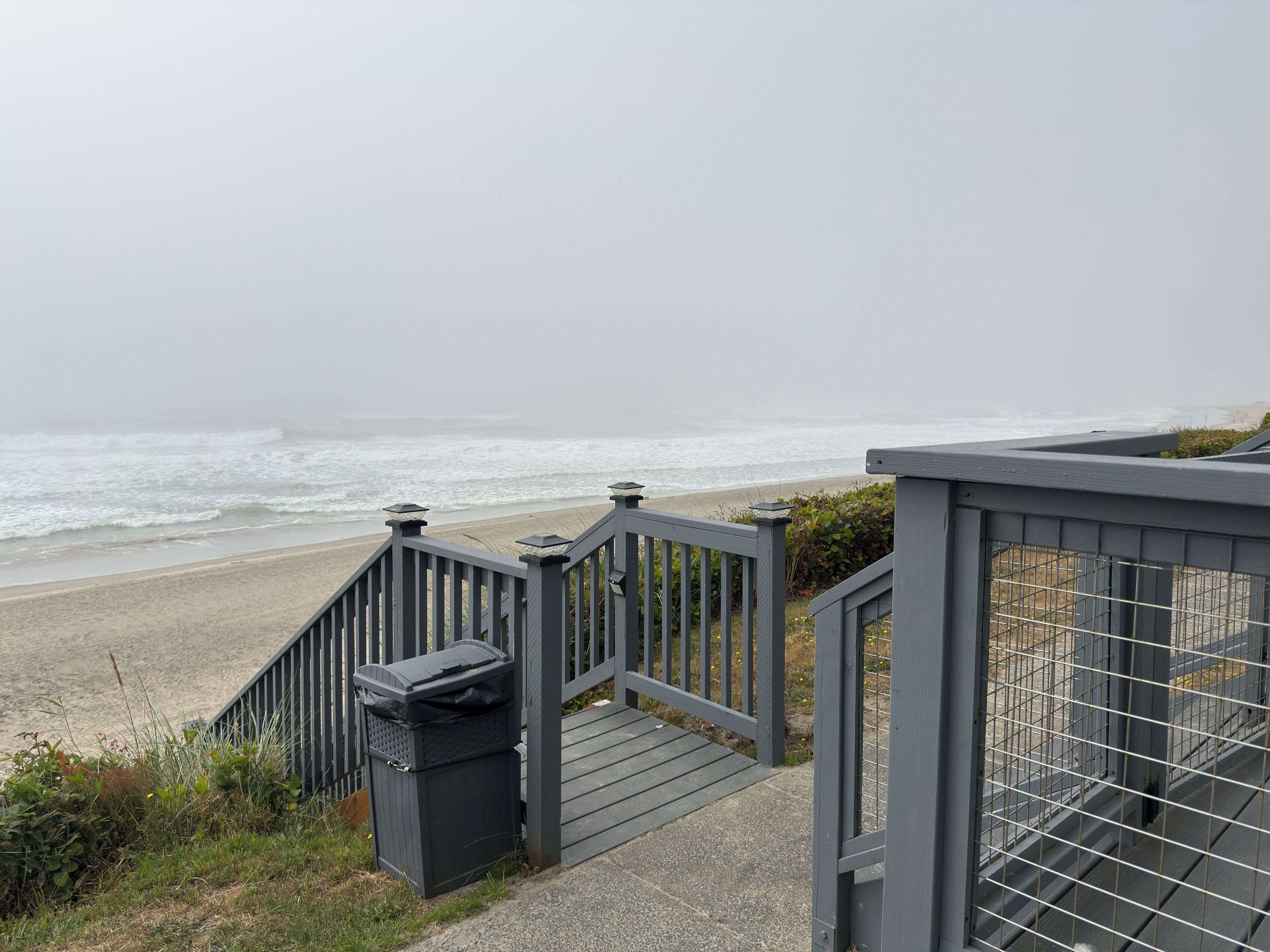 Una escalera de madera que lleva a una playa con vistas al océano.