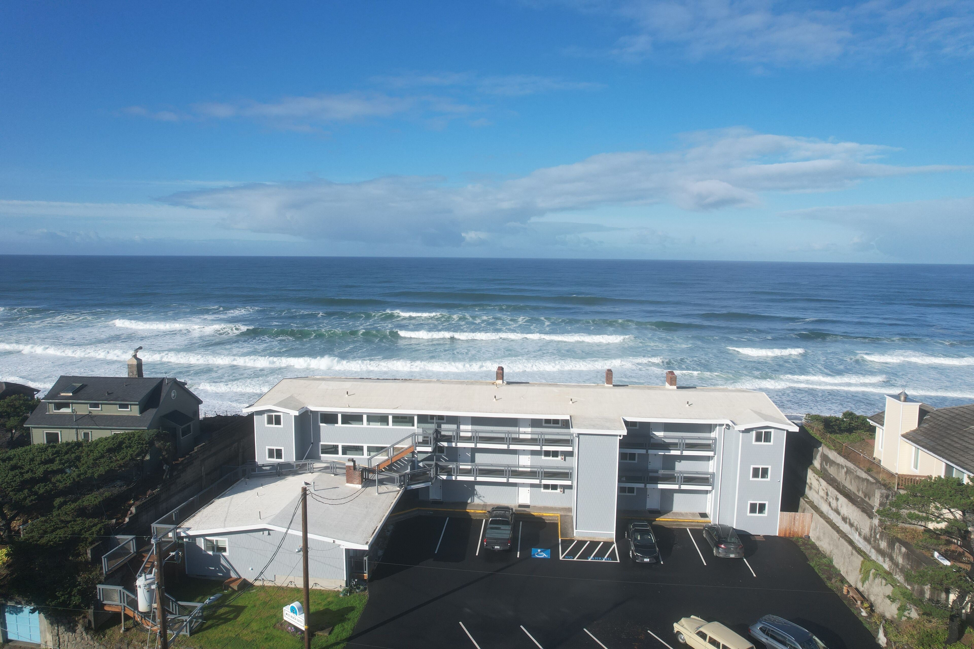 Edifício costeiro com estacionamento e vista para o oceano.
