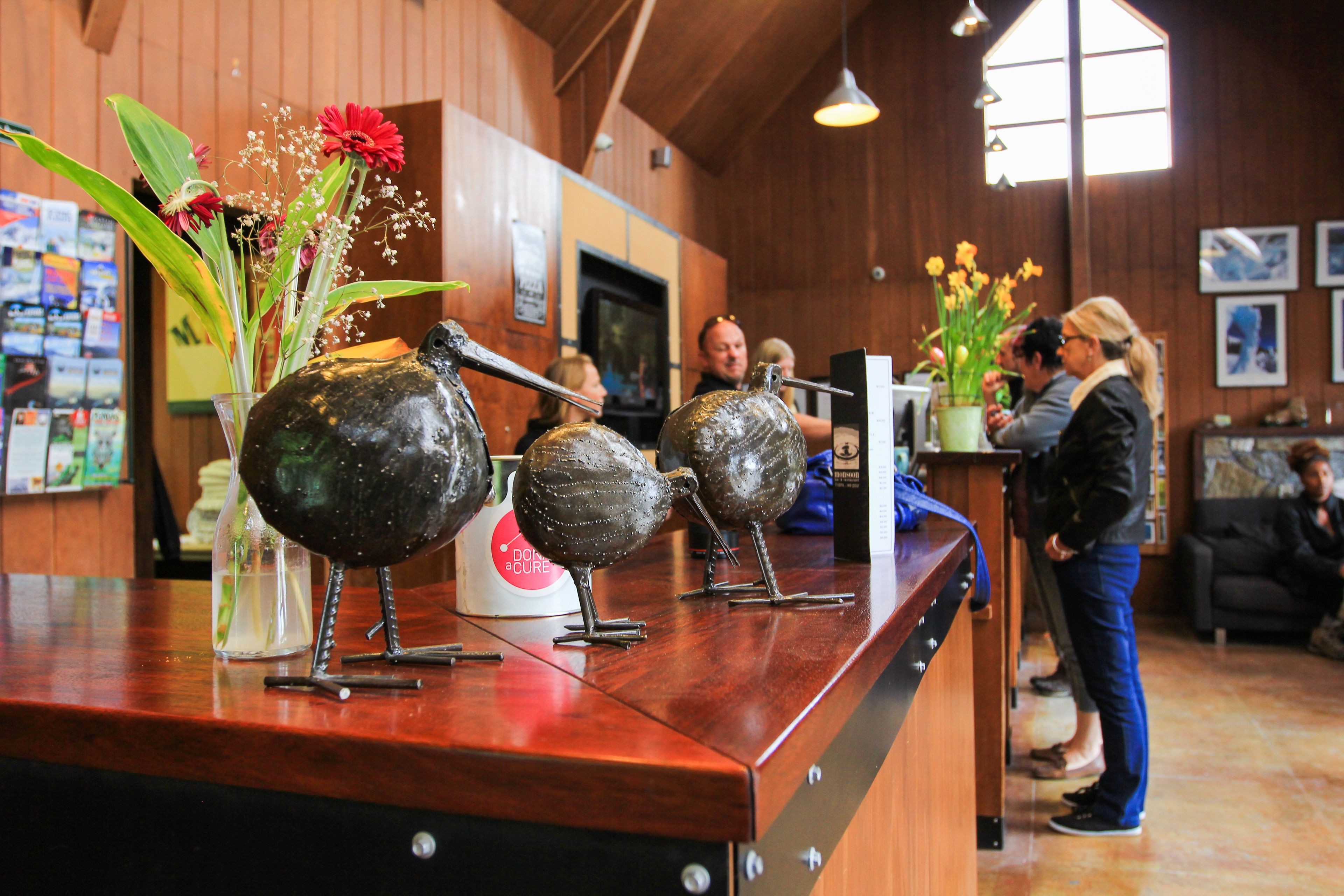 A reception area with a wooden counter, decorative metal birds, and a vase with flowers.