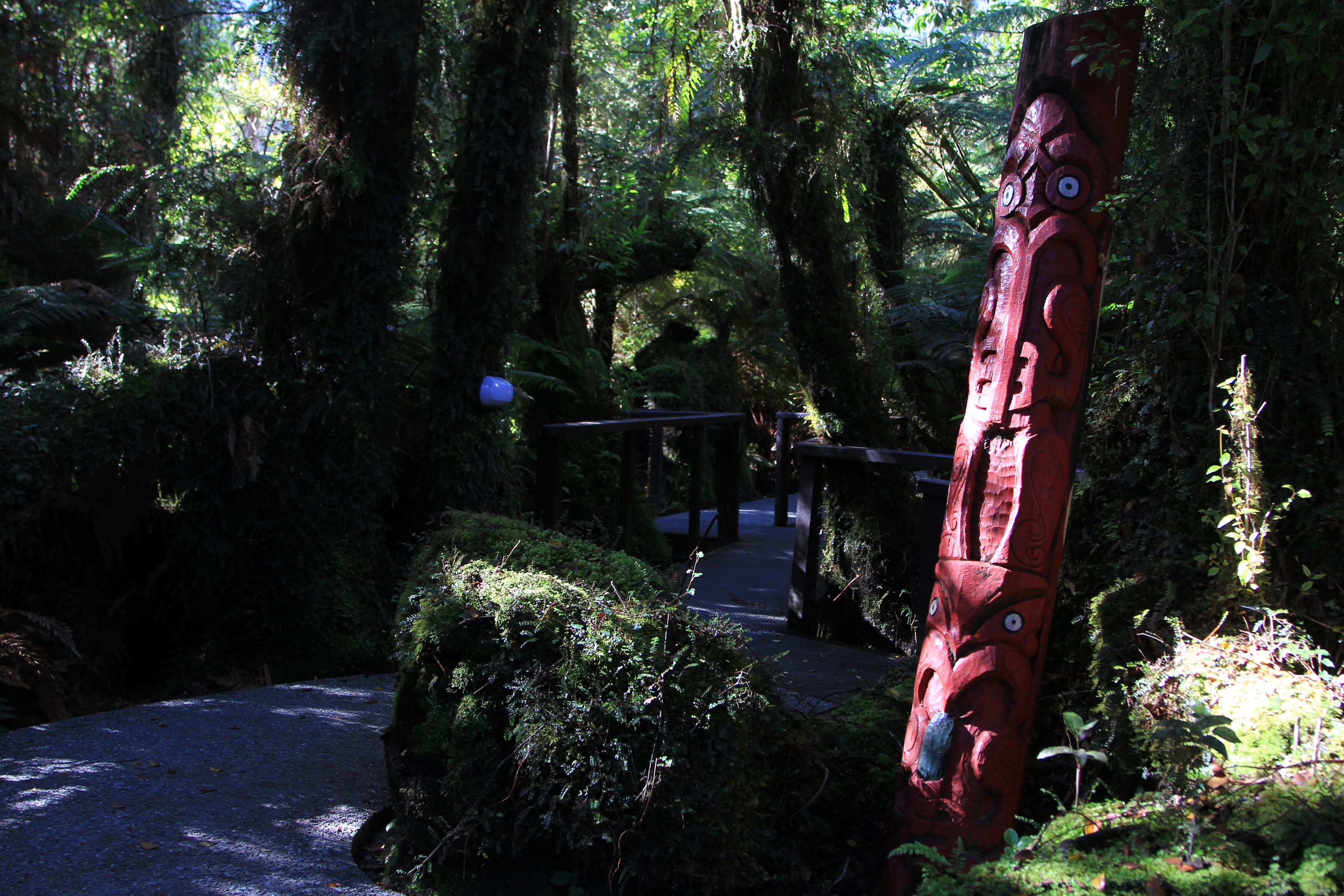 A forested area with a wooden structure resembling a totem pole.