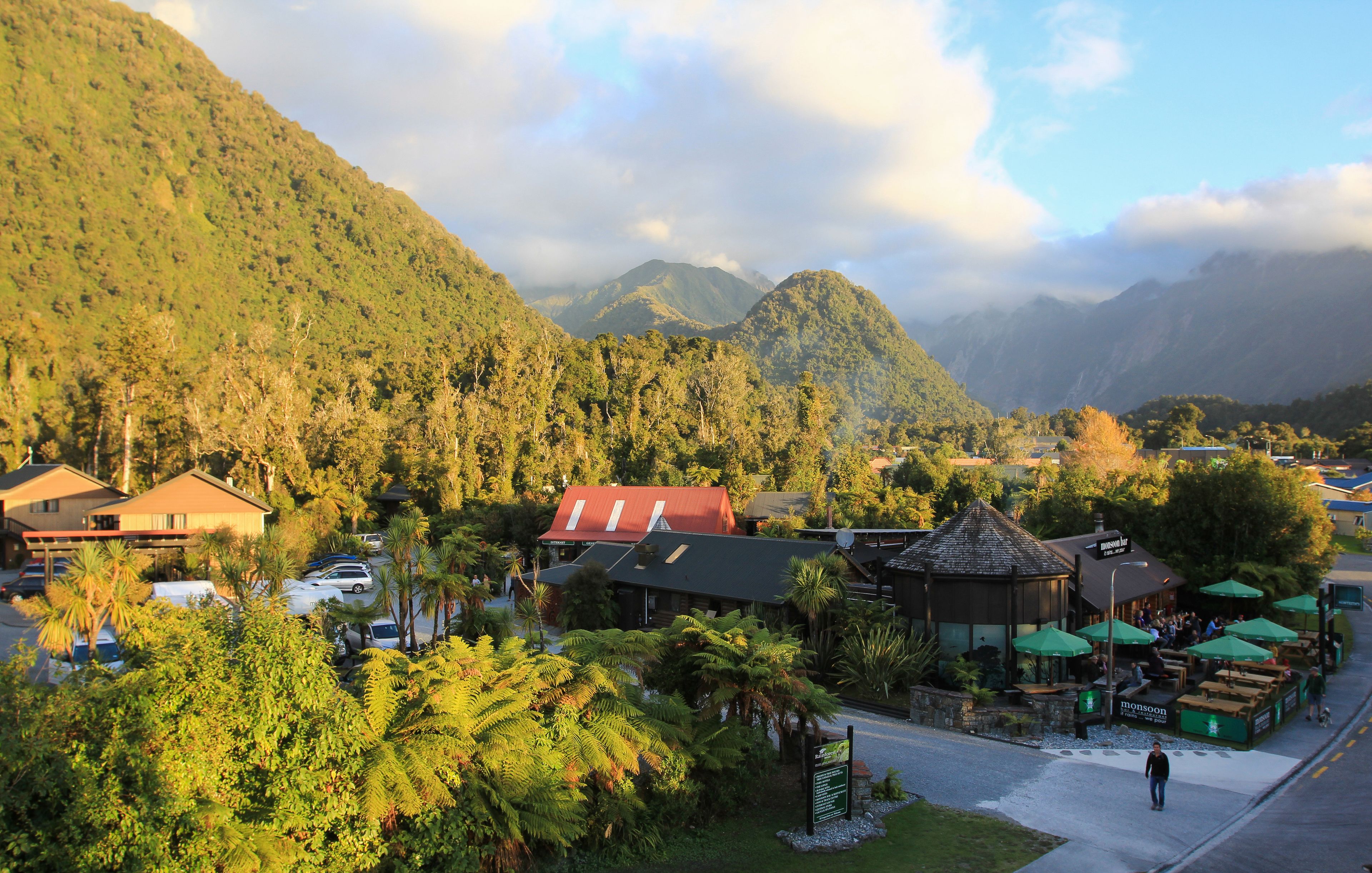 Paisaje montañoso con un restaurante que ofrece mesas al aire libre y sombrillas.