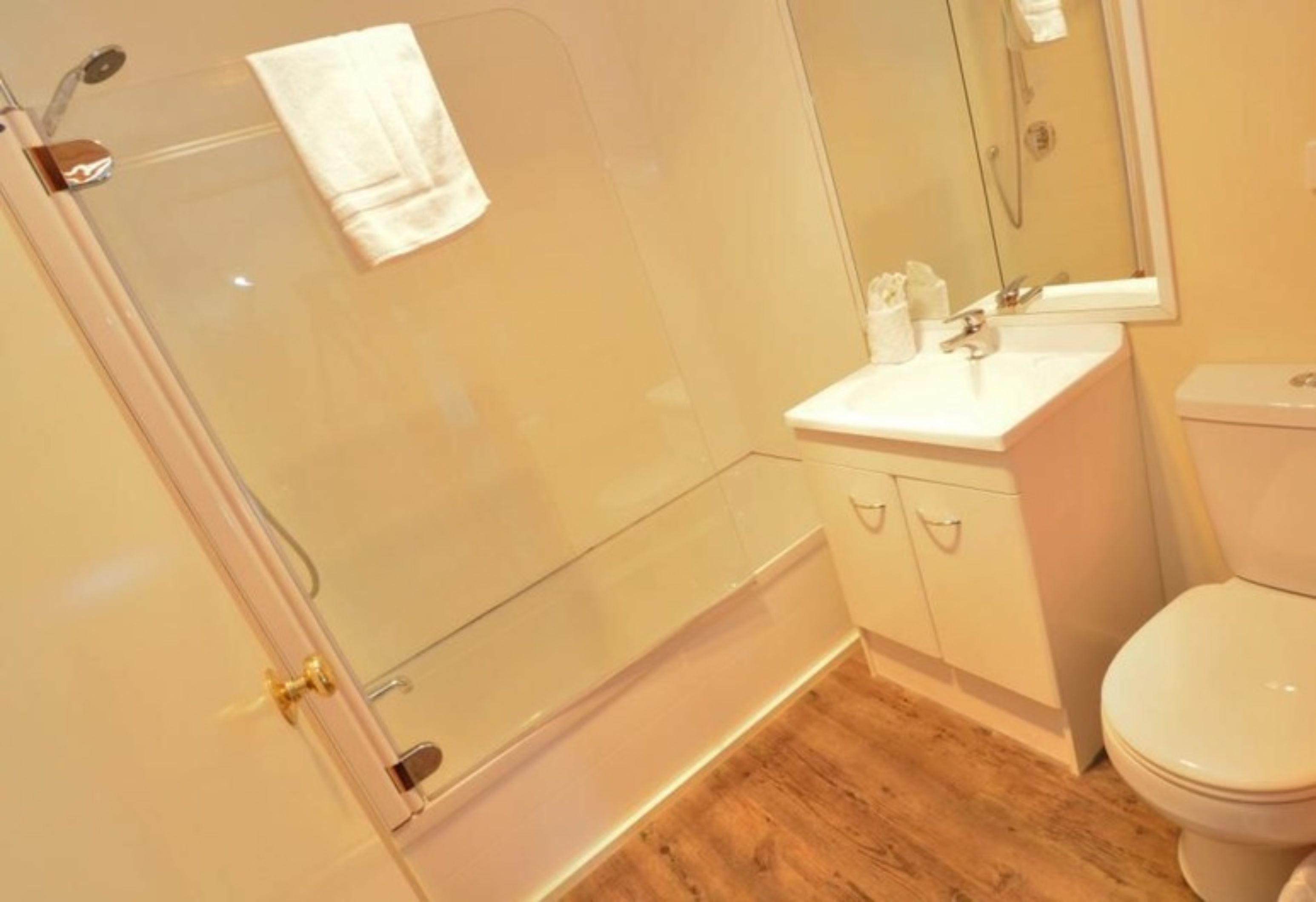 A bathroom with a glass shower enclosure, a white sink, and a toilet.