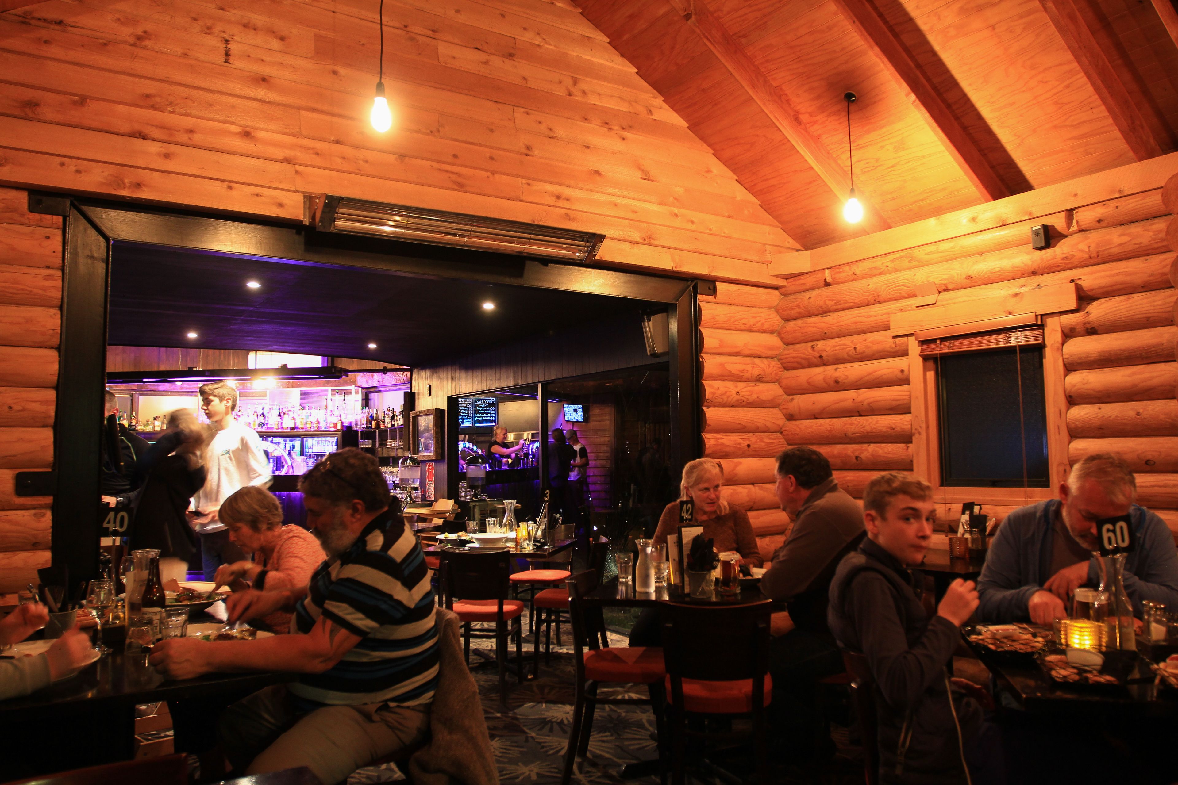 A cozy log cabin-style bar with wooden walls and a warm ambiance.