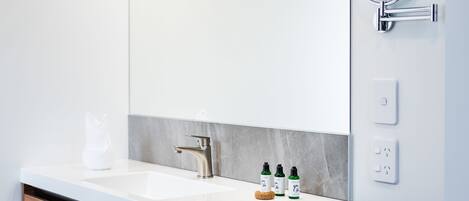 A modern bathroom with a wooden vanity, a large mirror, and a built-in light fixture.