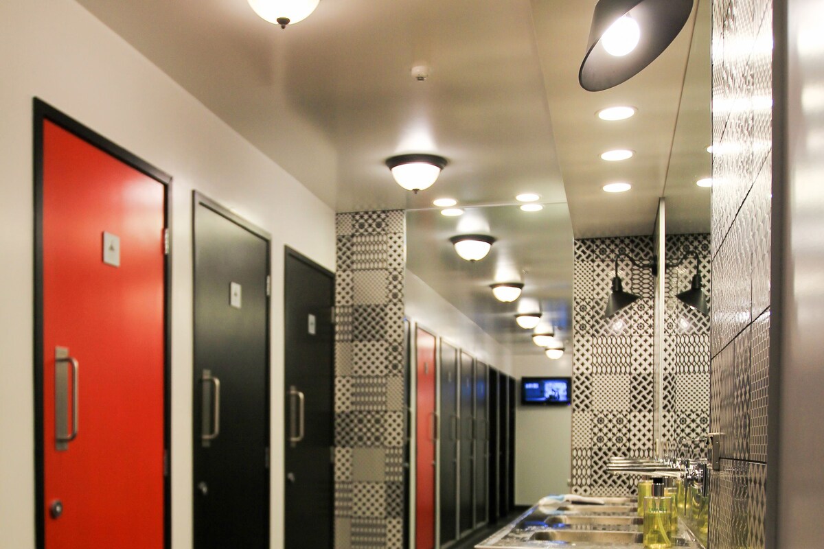 Pasillo de hotel con taquillas, un lavabo y un espejo.