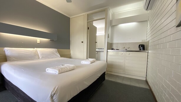 Une chambre d’hôtel avec un lit, une petite kitchenette et une salle de bain.