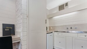 Une cuisine moderne avec des meubles blancs, un four à micro-ondes encastré et un réfrigérateur compact.
