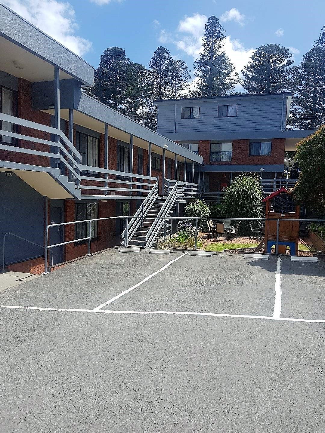 A multi-story building with a covered outdoor area, a staircase, and a playground.