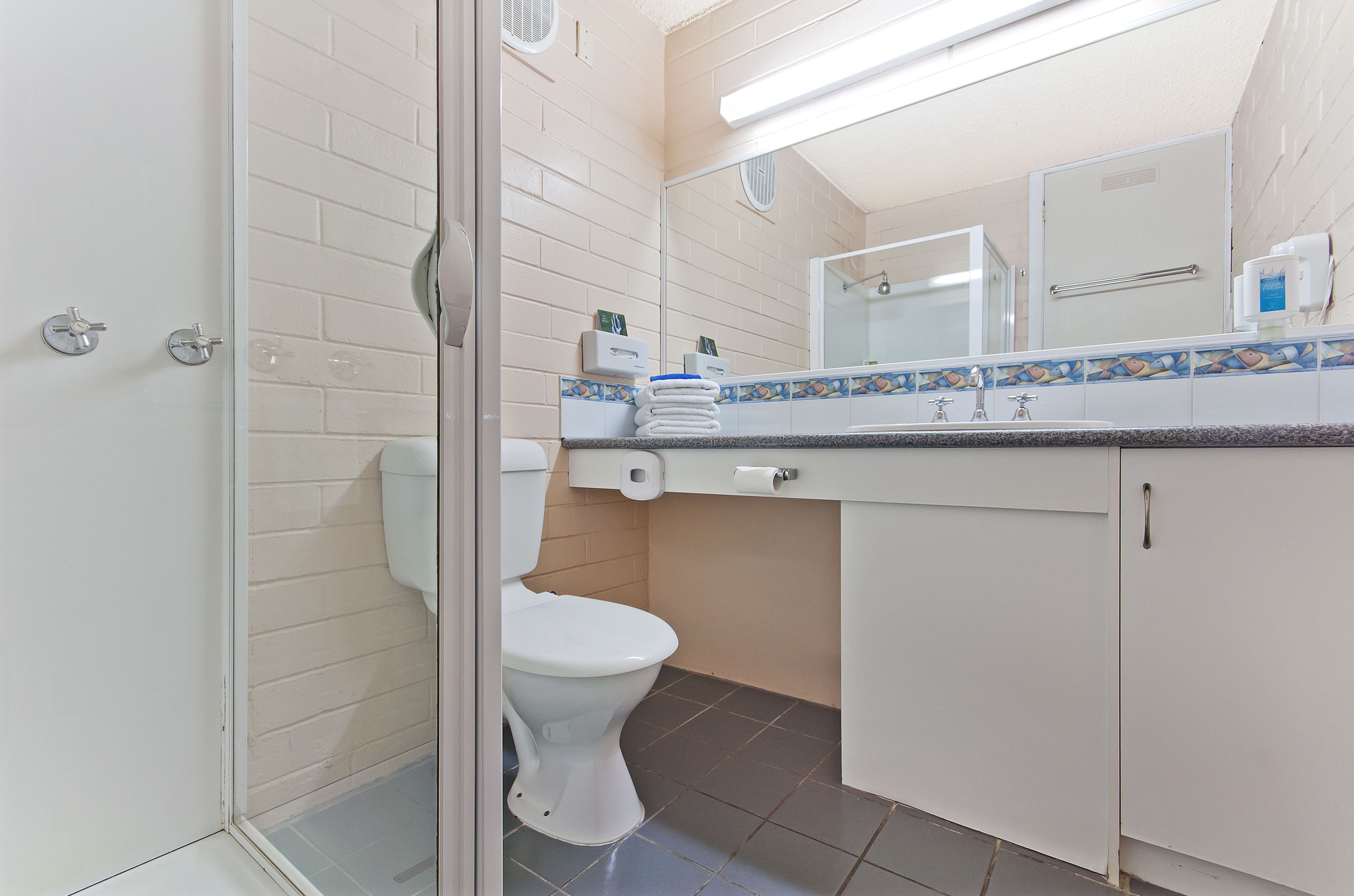 Ein Badezimmer mit Toilette, Waschbecken mit Spiegel darüber und einem Schrank darunter.