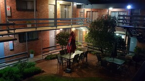 Une terrasse extérieure à plusieurs niveaux, dotée de tables et de chaises, et entourée de murs en briques et de plantes en pot.