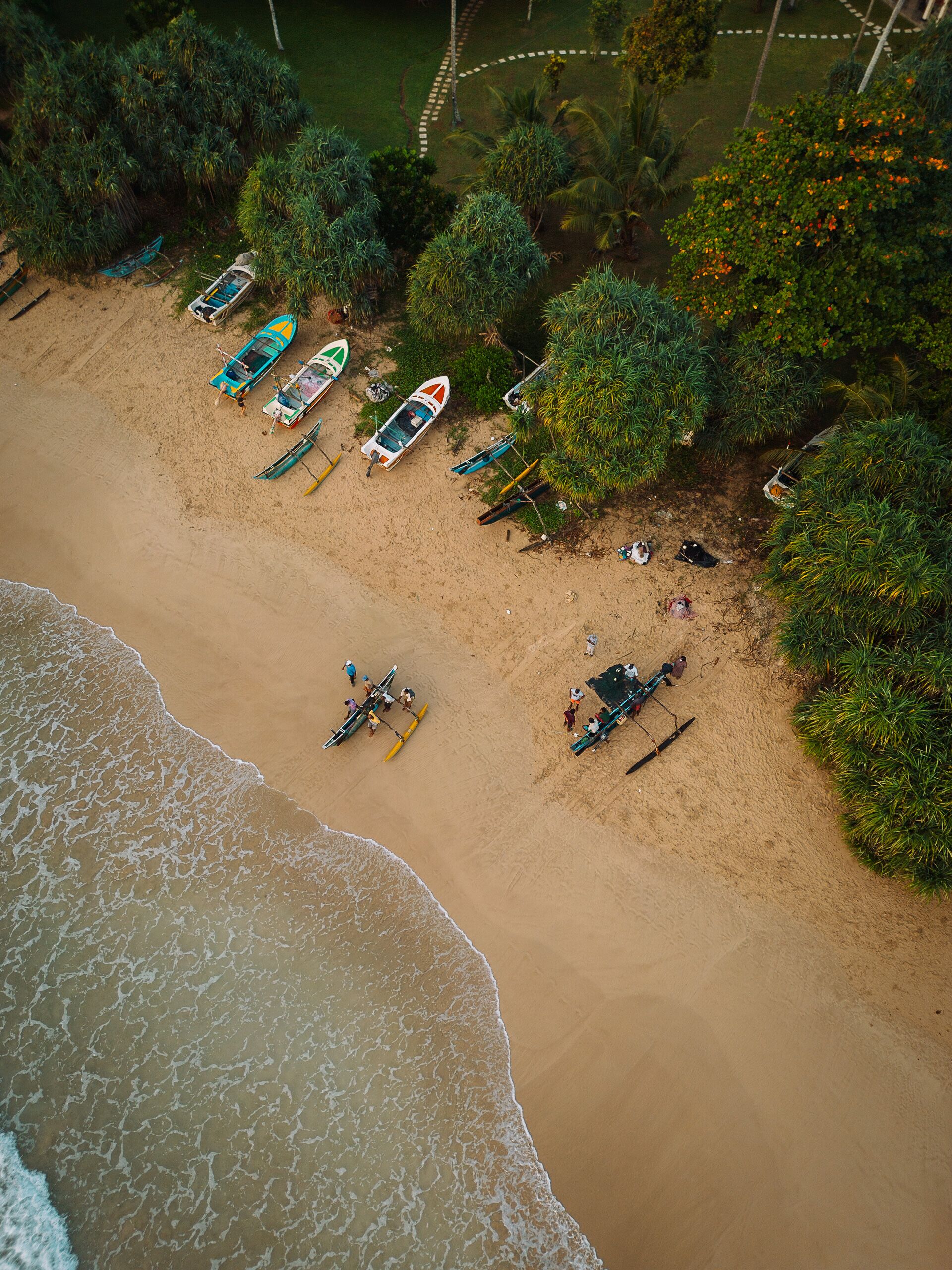An aerial view of a beach with several boats and people.