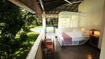 A balcony with a bed, a table, and a chair.