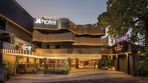 A hotel with a modern design, featuring a prominent 'J4 Hotel' sign, outdoor seating area, and a well-lit entrance. - J4 Hotels Legian (Kuta)