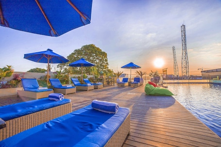 Una piscina al aire libre, sombrillas, sillones reclinables de piscina