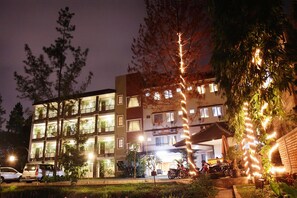 A multi-story hotel with balconies, a covered entrance, and a parking area with cars and motorcycles. - Lotus Bandung (Bandung)