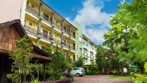 Un hôtel à plusieurs étages doté de balcons, d’un espace extérieur couvert et d’une végétation luxuriante.