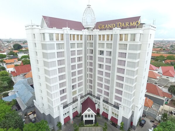 Un hotel grande de varios pisos, con un letrero prominente que dice 'Grand Darmo' en la parte superior. El edificio tiene una fachada simétrica con varios balcones.