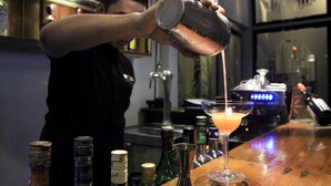 Un barman sirviendo una bebida en una copa de martini.