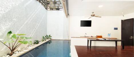 Un interior moderno con piscina, zona de comedor y televisor de pantalla plana.