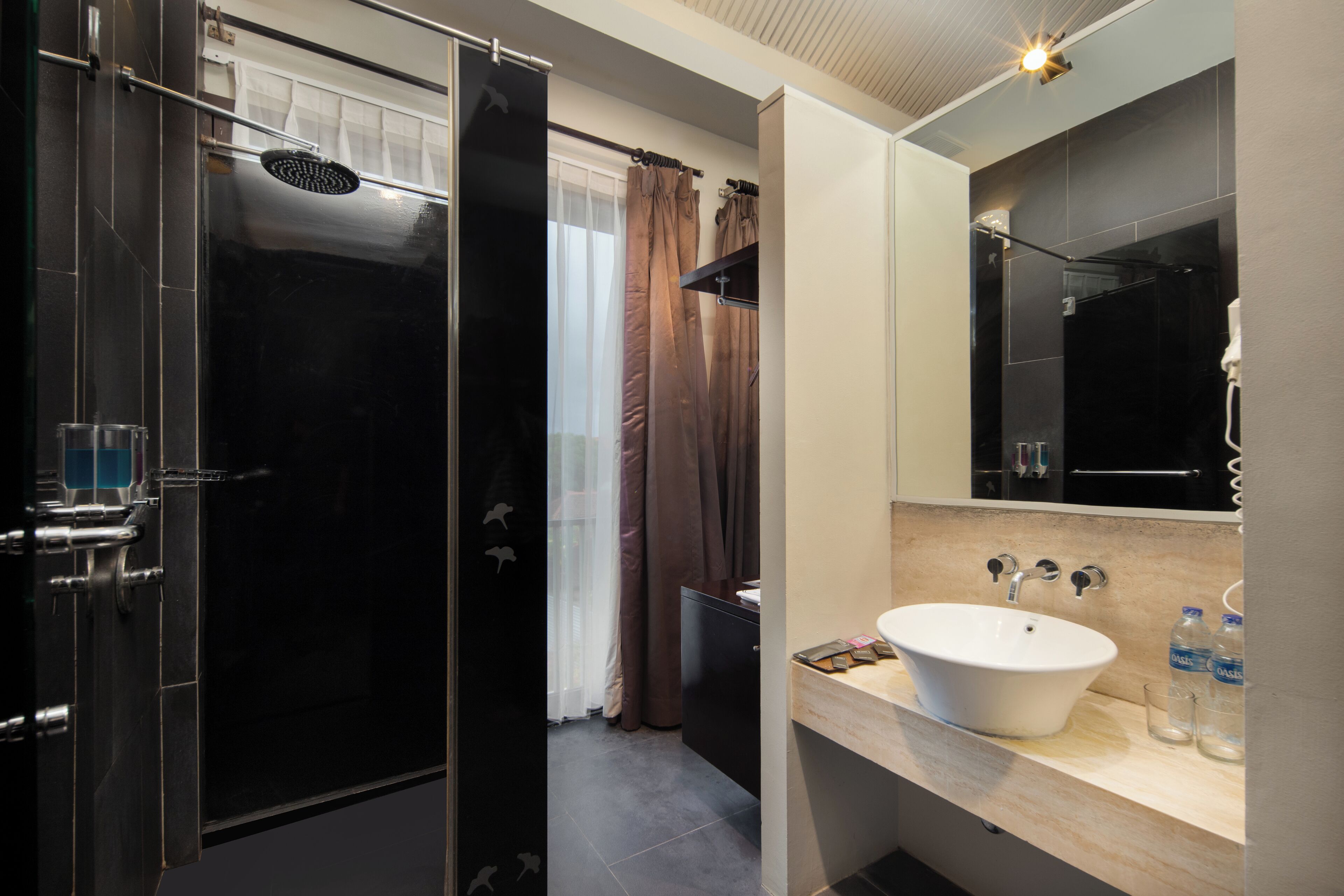 A modern bathroom with a black shower enclosure, a vanity with a white sink, and a large mirror.