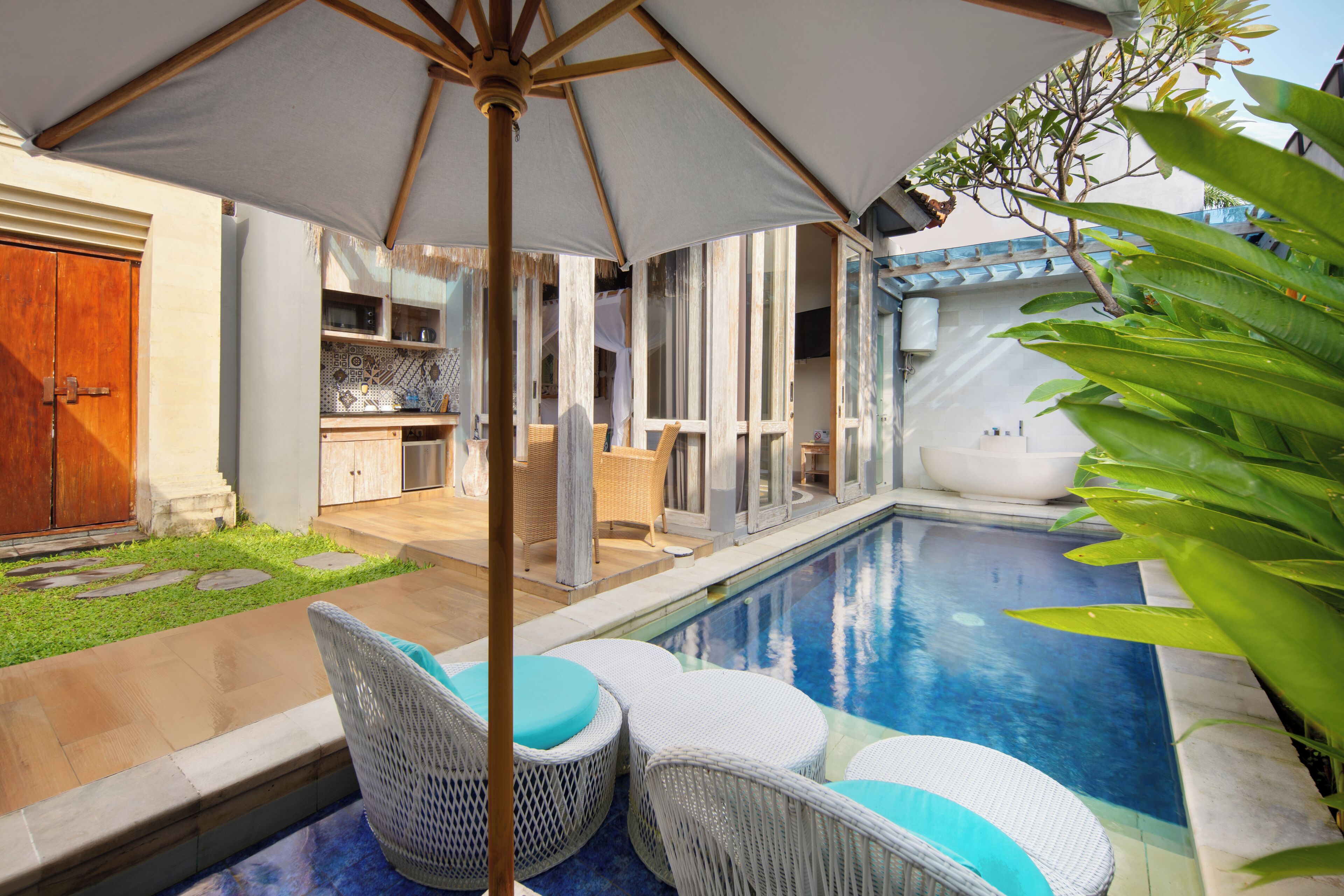 A pool area with wicker chairs and a large umbrella.
