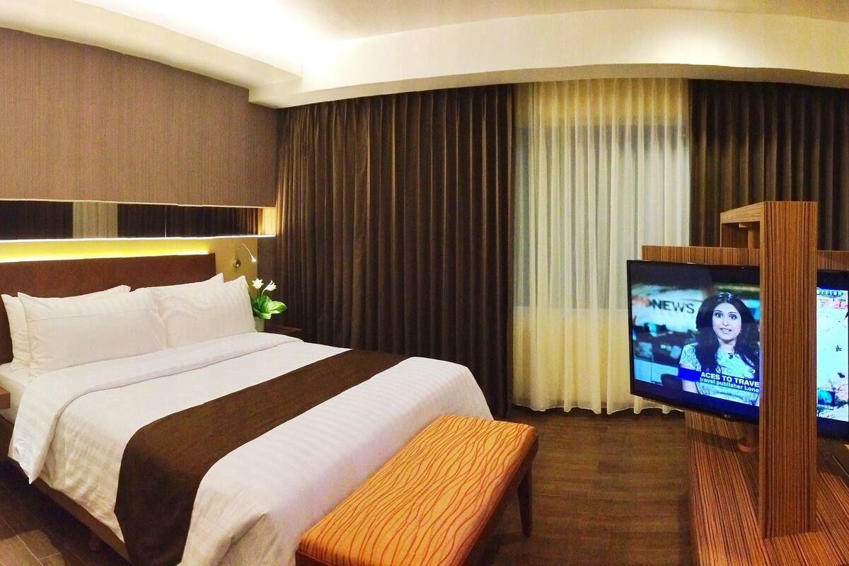 Une chambre d’hôtel avec un grand lit, une télévision, un canapé et une petite table.