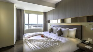 Une chambre d’hôtel avec un grand lit, une table de chevet avec un téléphone et une fenêtre avec des rideaux.