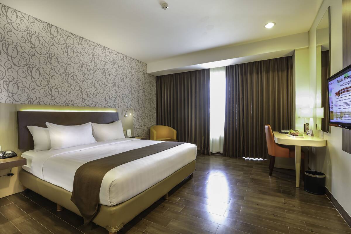 Une chambre d’hôtel avec un grand lit, un bureau, une chaise, une télévision et une salle de bain.