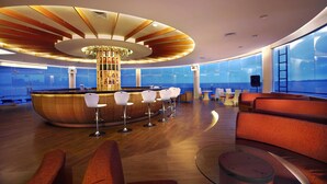 Un espace bar moderne doté d’une colonne centrale, de tabourets de bar et de sièges.