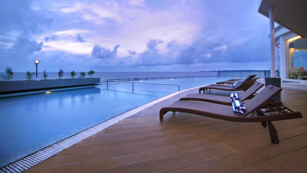 Un espace aménagé au bord de la piscine, avec des chaises longues et une vue sur la mer.