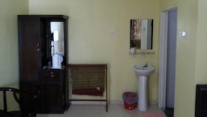 A small room with a wooden cabinet, a white pedestal sink, and a mirror on the wall. - Gelam Inn Motel Langkawi (Langkawi)