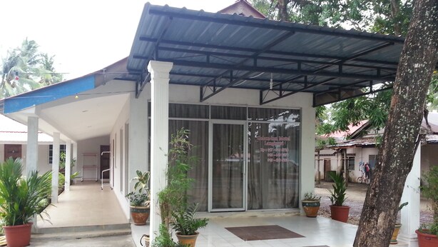 A covered building with a tiled entrance, potted plants, and a tree in the foreground. - Gelam Inn Motel Langkawi (Langkawi)