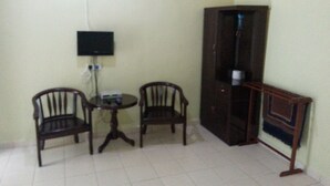 A small room with two wooden chairs, a small table, a television mounted on the wall, and a tall cabinet. - Gelam Inn Motel Langkawi (Langkawi)