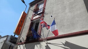 A building with a sign that reads "hotel" and flags of France and the European Union. - Hôtel Le Petit Château (Malakoff)