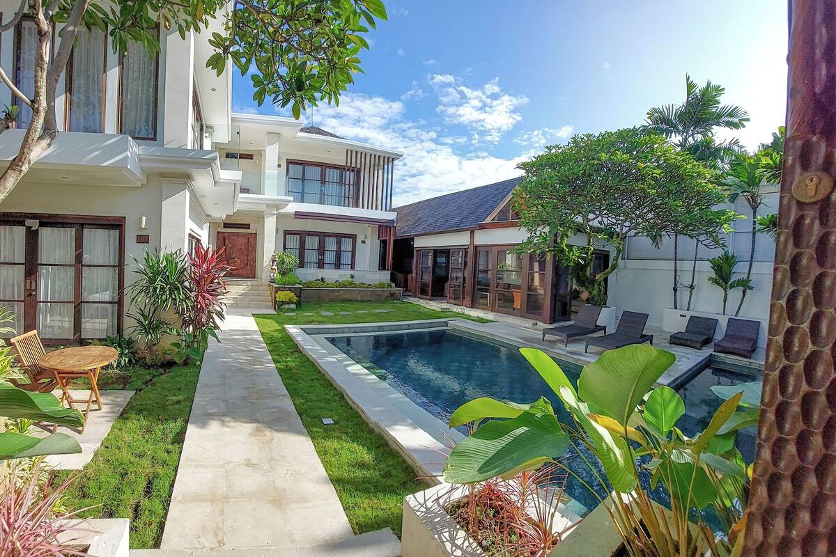 Uma casa moderna com piscina, gramado bem cuidado e diversas plantas.